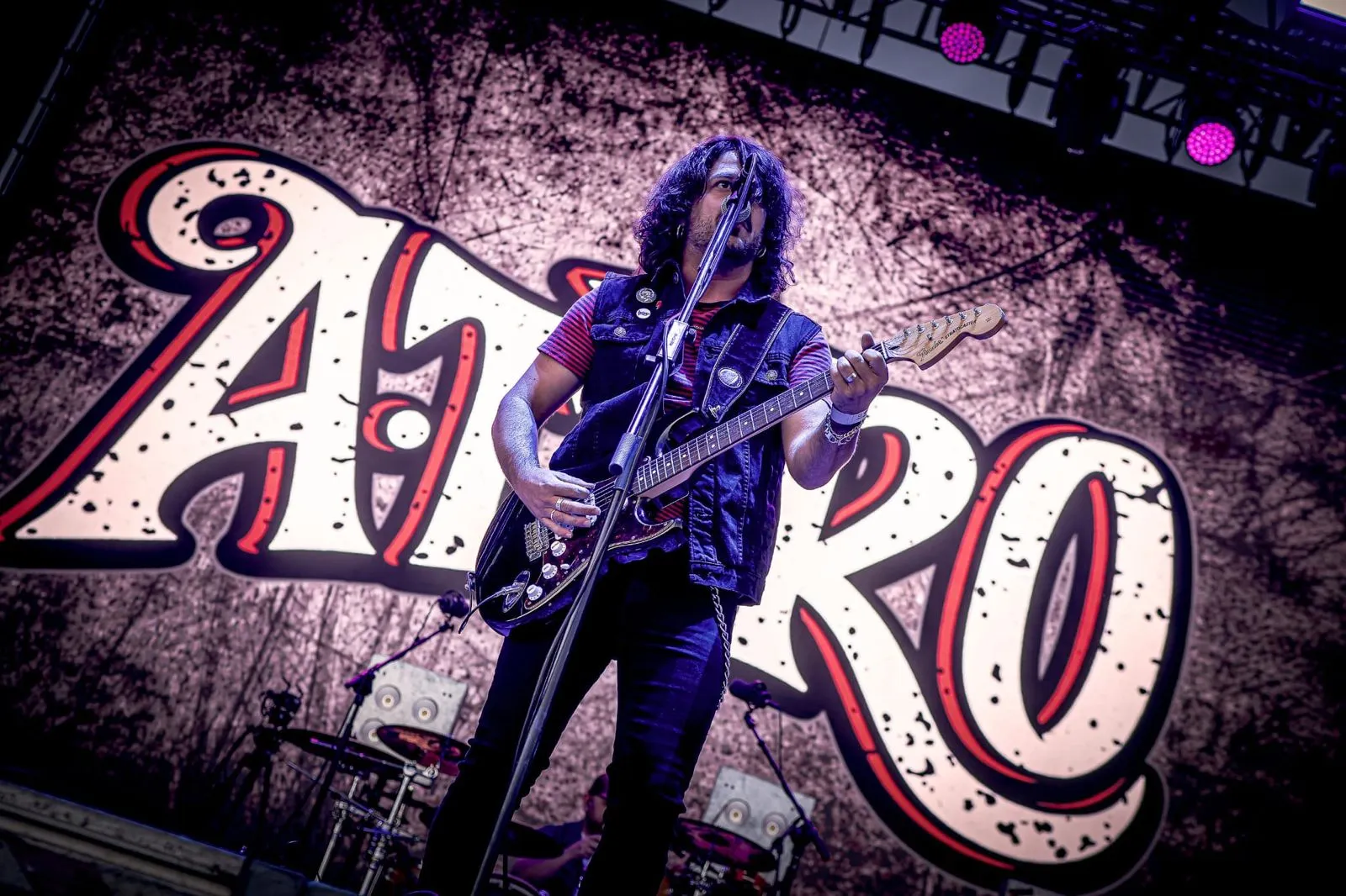 Guitarrista de A TiRO cantando ante el logotipo