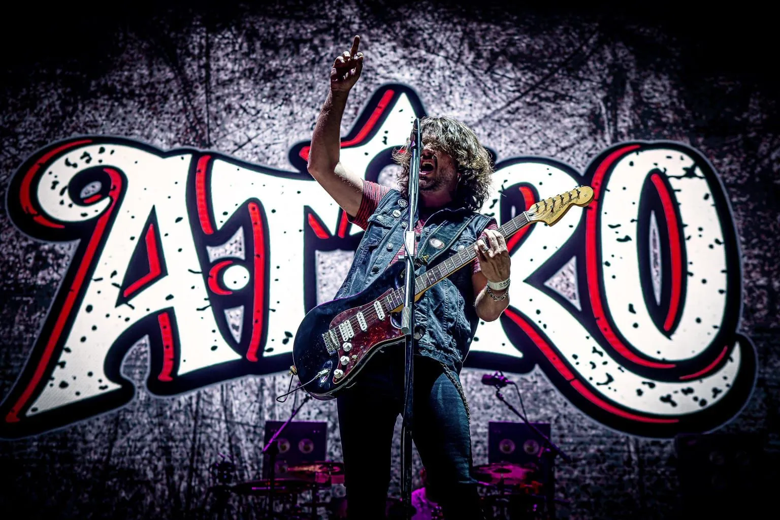 Cantante y guitarrista de A TiRO frente al gran logotipo del grupo
